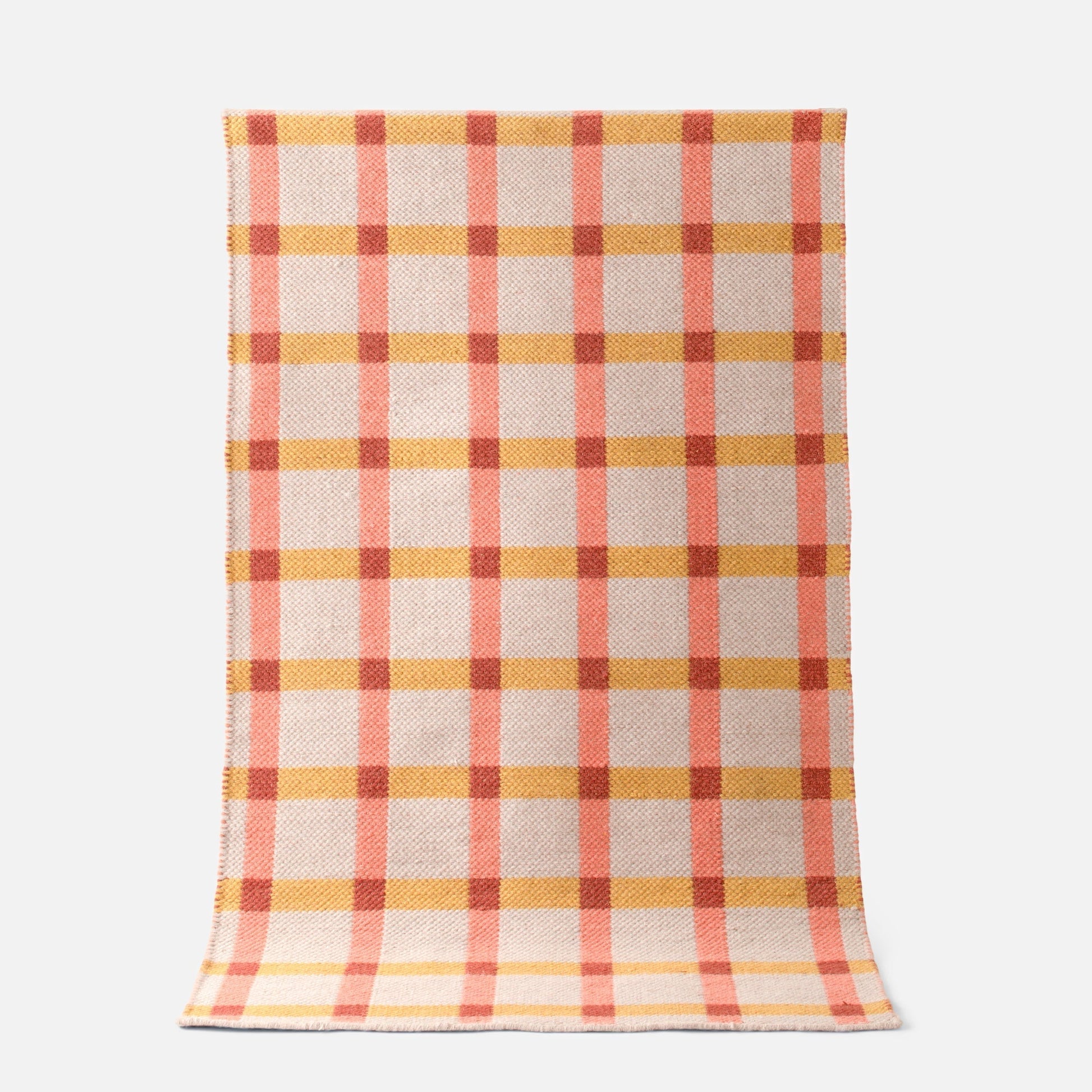 Top-down view of Plaid Wool Reversible Rug showcasing peach and mustard plaid handwoven wool on a white background