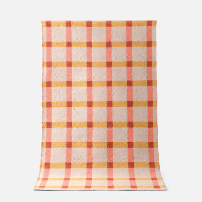 Top-down view of Plaid Wool Reversible Rug showcasing peach and mustard plaid handwoven wool on a white background