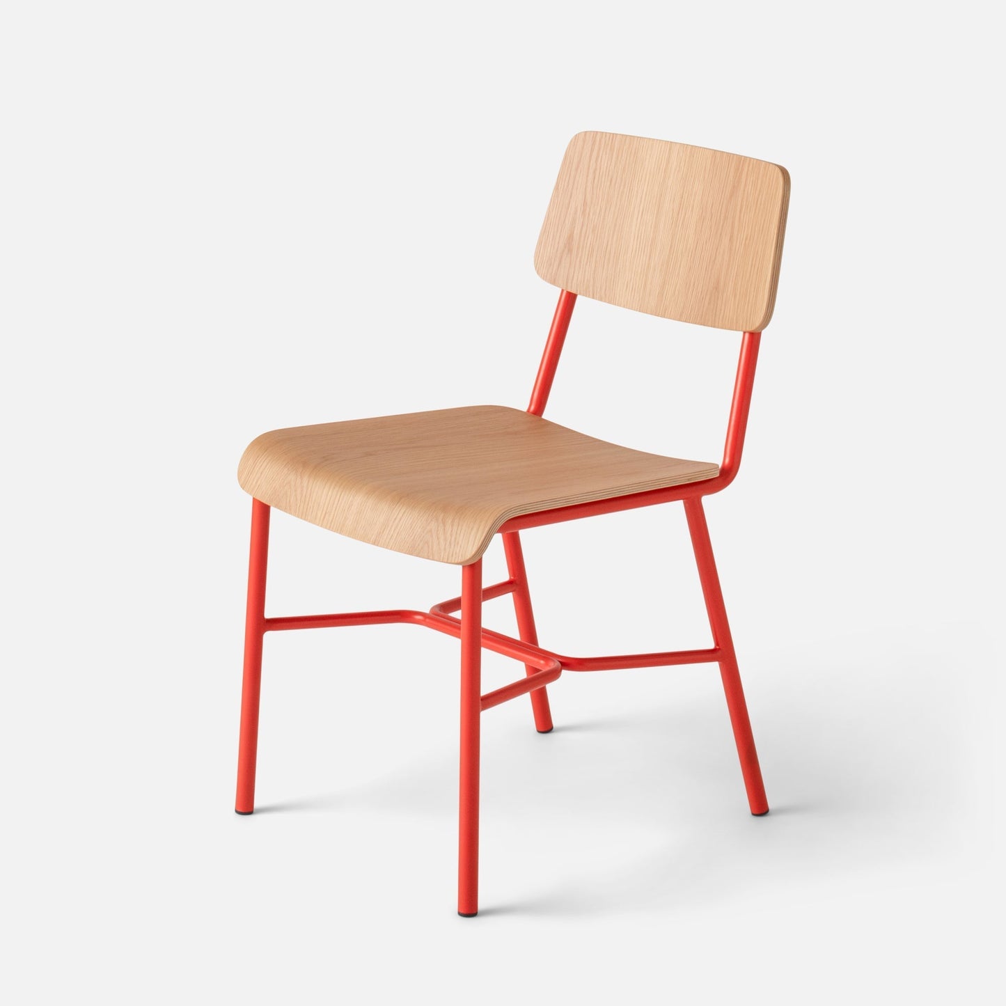 Angled close-up of Cole Dining Chair showcasing contoured oak veneer seat and backrest and red powder-coated metal frame on light gray background
