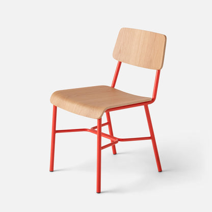 Angled close-up of Cole Dining Chair showcasing contoured oak veneer seat and backrest and red powder-coated metal frame on light gray background