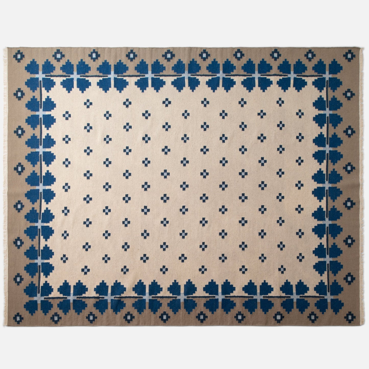 Top-down view of Flora Wool Flatweave Rug showcasing blue floral border and small navy cross motifs on a beige field