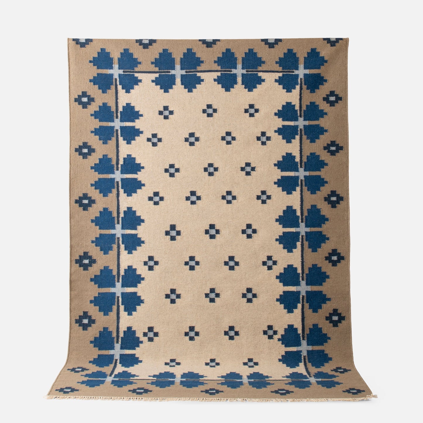 Partial top view of Flora Wool Flatweave Rug showing blue folk floral pattern on tan wool background