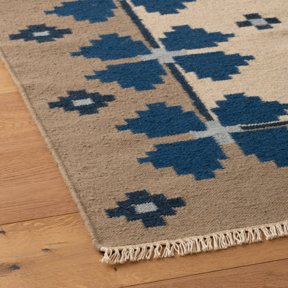 Close up of Flora Wool Flatweave Rug showcasing woven wool texture, navy floral motif and fringed edge on a hardwood floor
