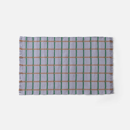 Top edge of Cotton Grid Flatweave Rug in lavender with green vertical and tan horizontal grid lines and fringed edge on white background
