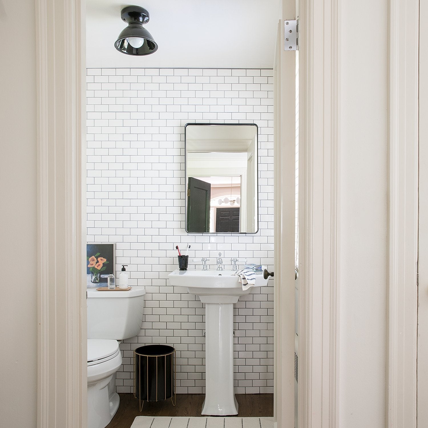 Front view of Leo Mirror showcasing thin black metal frame with rounded corners against a white subway-tiled bathroom wall