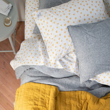 Top view of Thistle Percale Sheet Set showing yellow thistle print on white percale with gray linen and mustard quilt