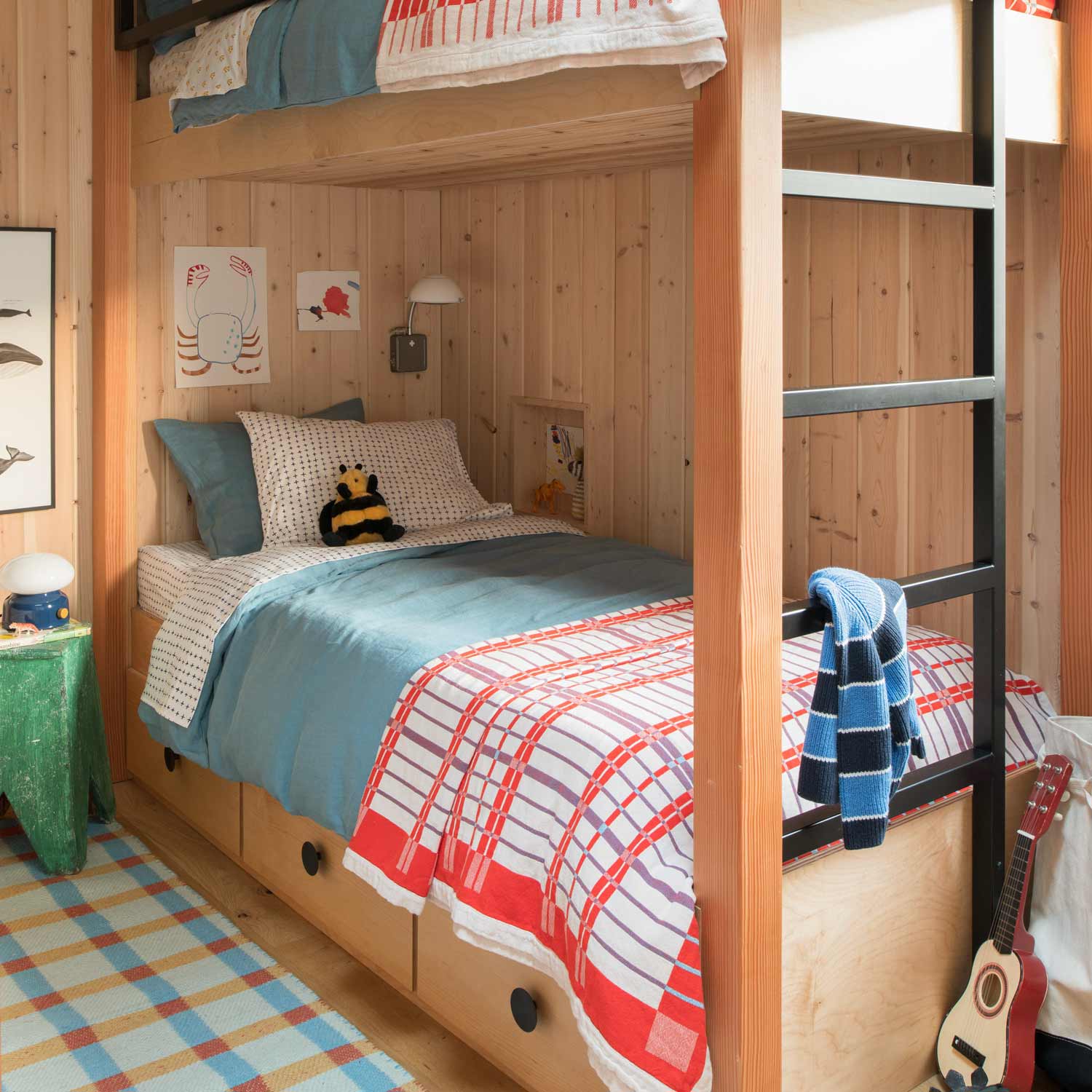 Plaid wool reversible rug on bedroom floor beneath a bunk bed in a wood-paneled room