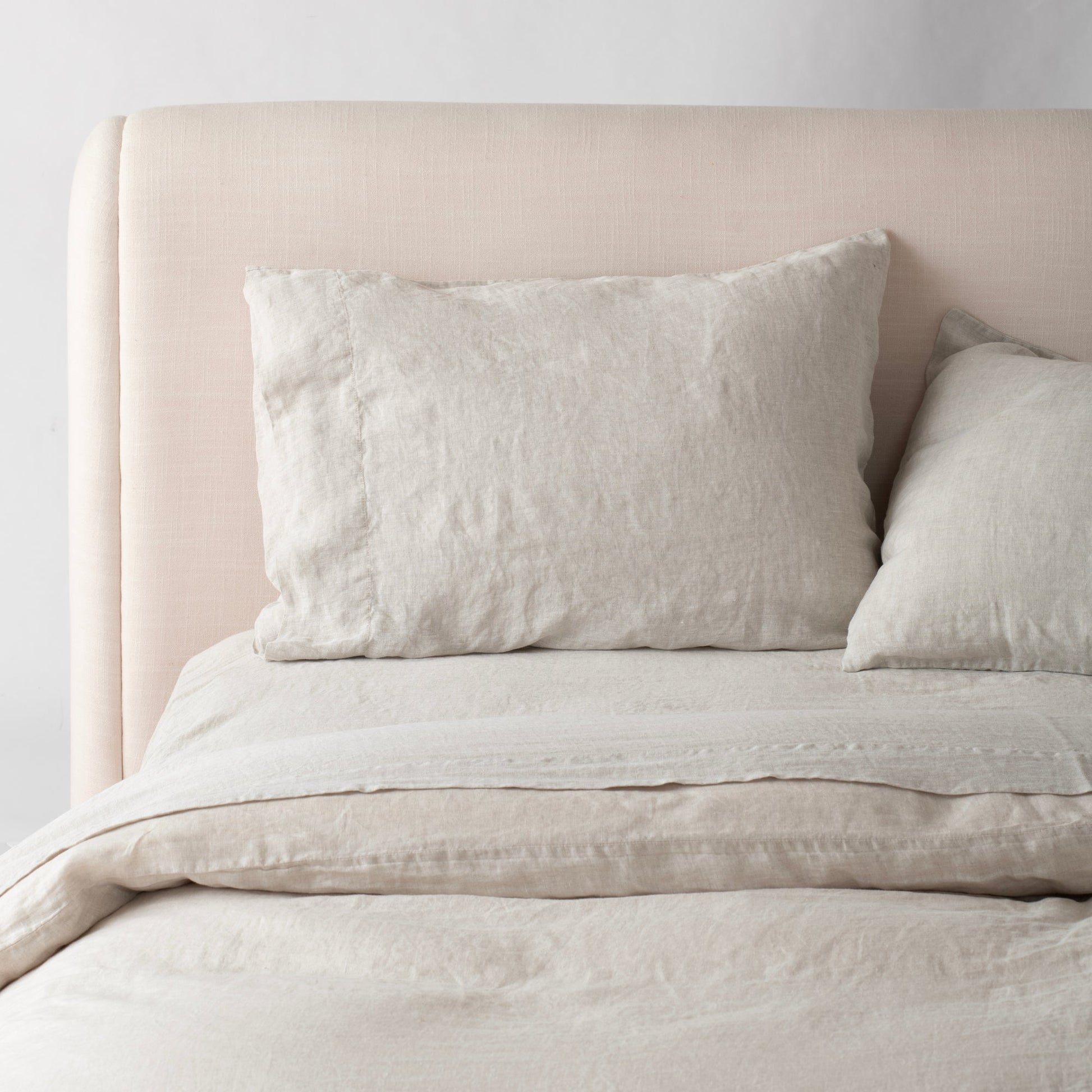 Close-up of Linen Pillow Sham showcasing natural linen texture and relaxed finish with pale headboard