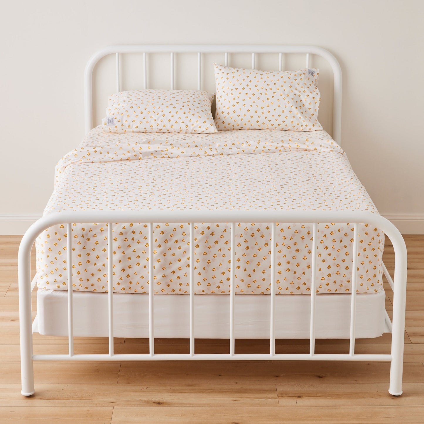 Front view of Thistle Percale Sheet Set showcasing yellow hand-drawn thistle pattern on white percale with white bed frame