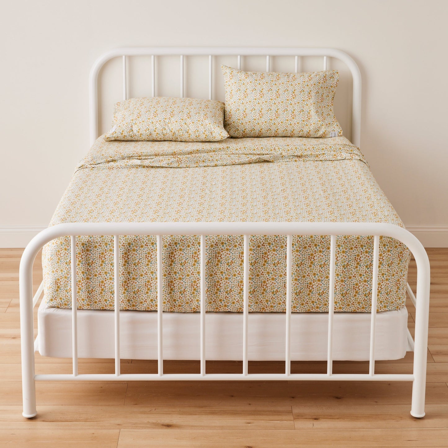 Front view of two Wallowa Floral Percale pillowcases showing chamomile floral print on percale with white metal bed frame