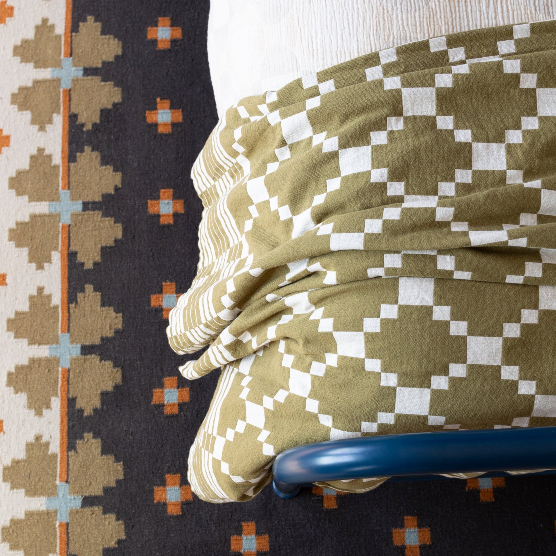 Overhead view of Flora Wool Flatweave Rug showing geometric folk-floral pattern and flatwoven texture with bed and chair