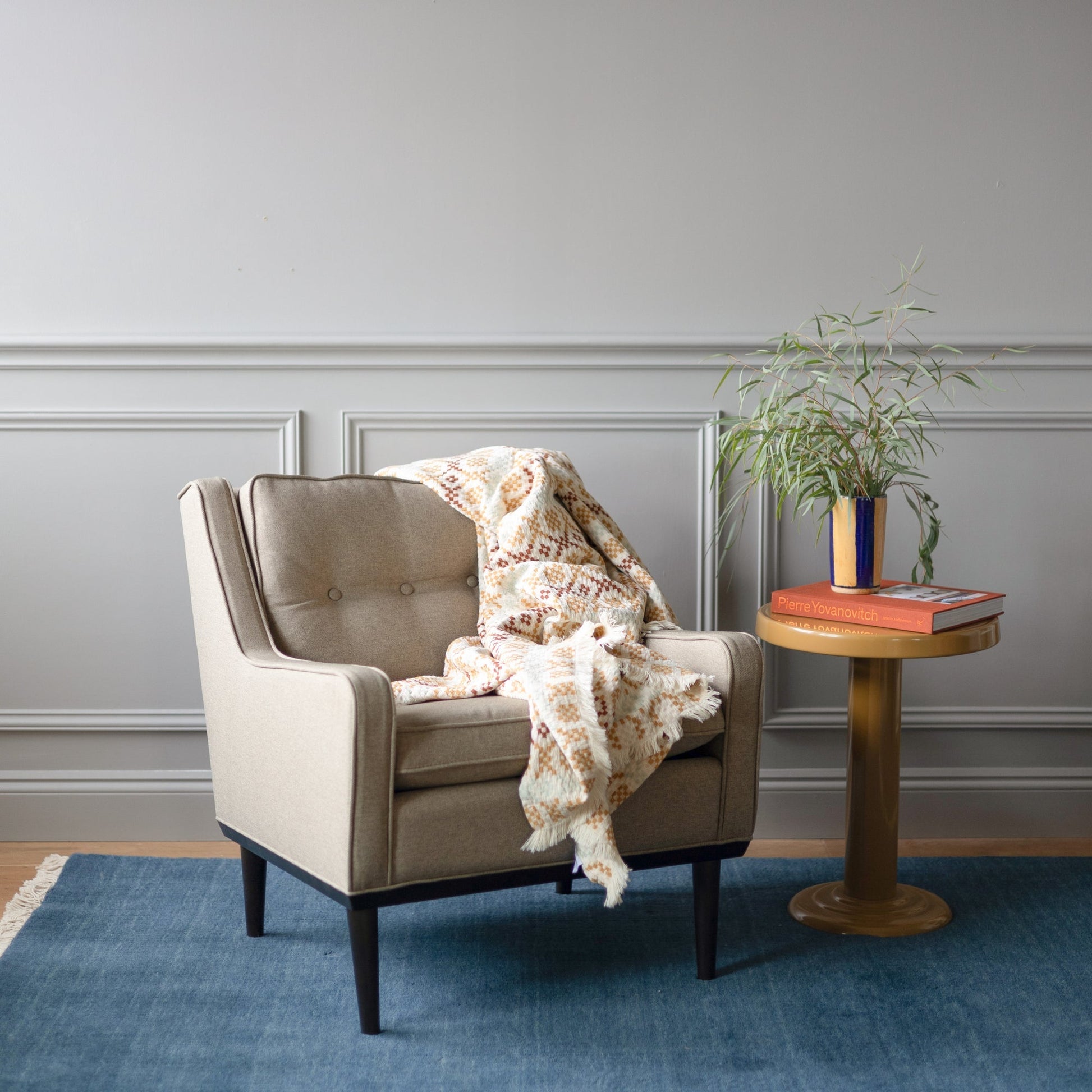 Armchair and side table on a blue Mesa wool rug in a cozy living room setting