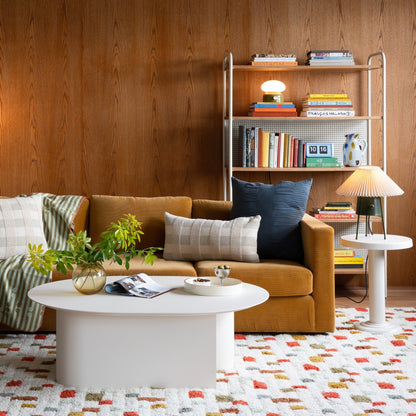 Living room with Pixel Handloom Shag rug, high-pile white wool with multicolored dots, mustard sofa, round coffee table and shelf