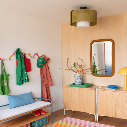 Angled view of Forma Mirror showing rounded rectangular frame and reflection, mounted on a light wood wall in a styled entryway