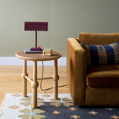 Flora Wool Flatweave Rug partially visible under a round oak side table beside a mustard sofa in a styled living room