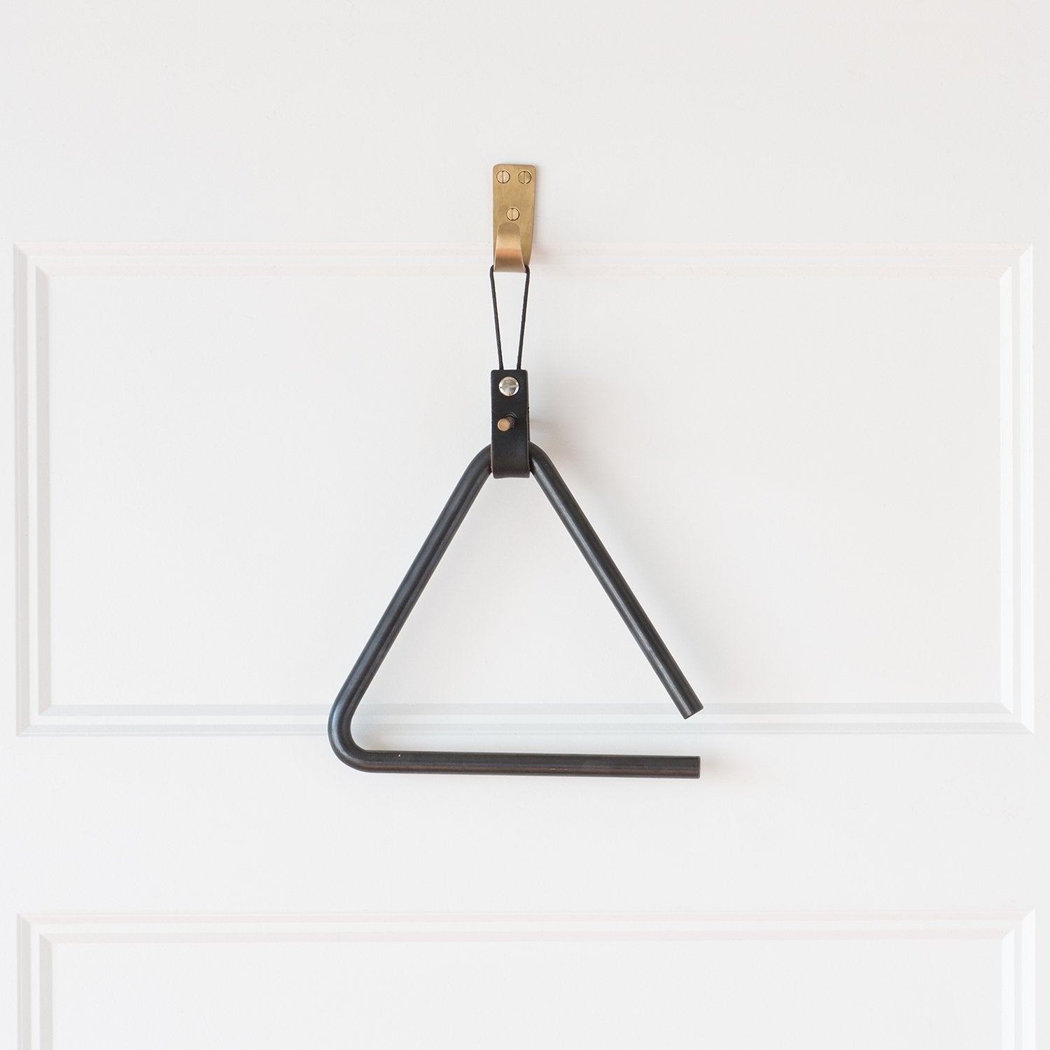 Front view of Thomas Hook showing natural brass finish and three mounting screws on a white paneled door