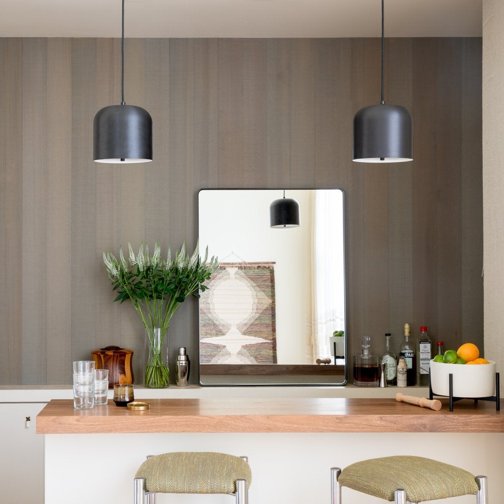 Rectangular Leo mirror reflecting a pendant light above a wooden countertop, with glassware, a vase of flowers, and a bowl of fruit