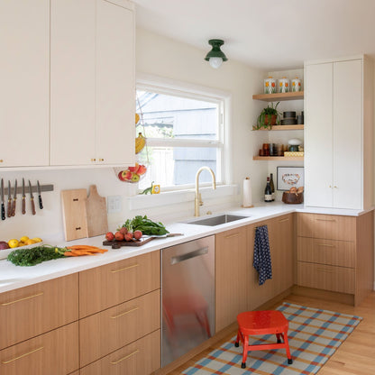 Plaid wool reversible rug on a kitchen floor by the sink and light wood cabinets, styled with a red step stool on top