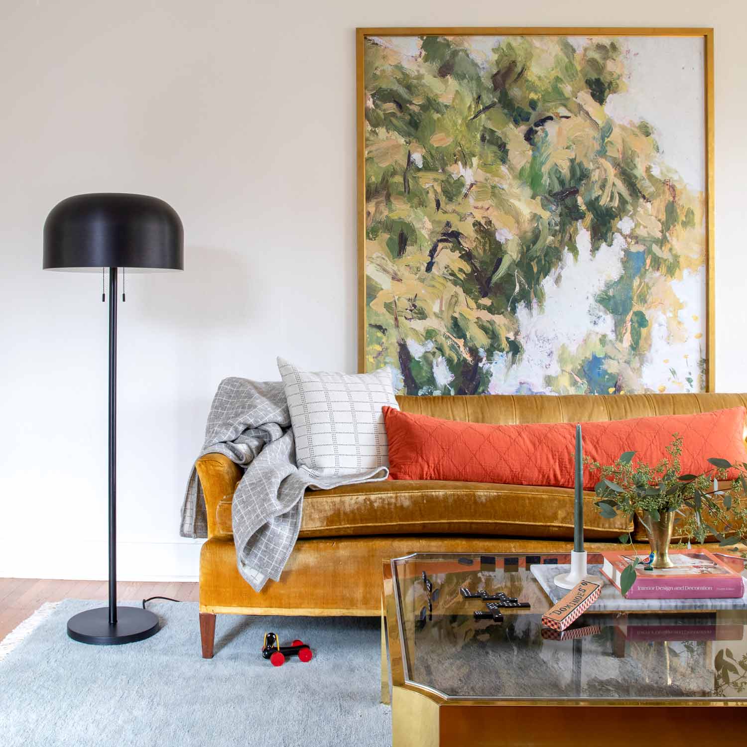 Light blue Mesa Wool Rug styled in a living room under a glass coffee table with a mustard velvet sofa and floor lamp