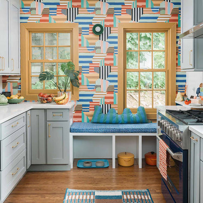 Kitchen featuring gold cabinet pulls, colorful geometric wallpaper, windows, and a built-in bench