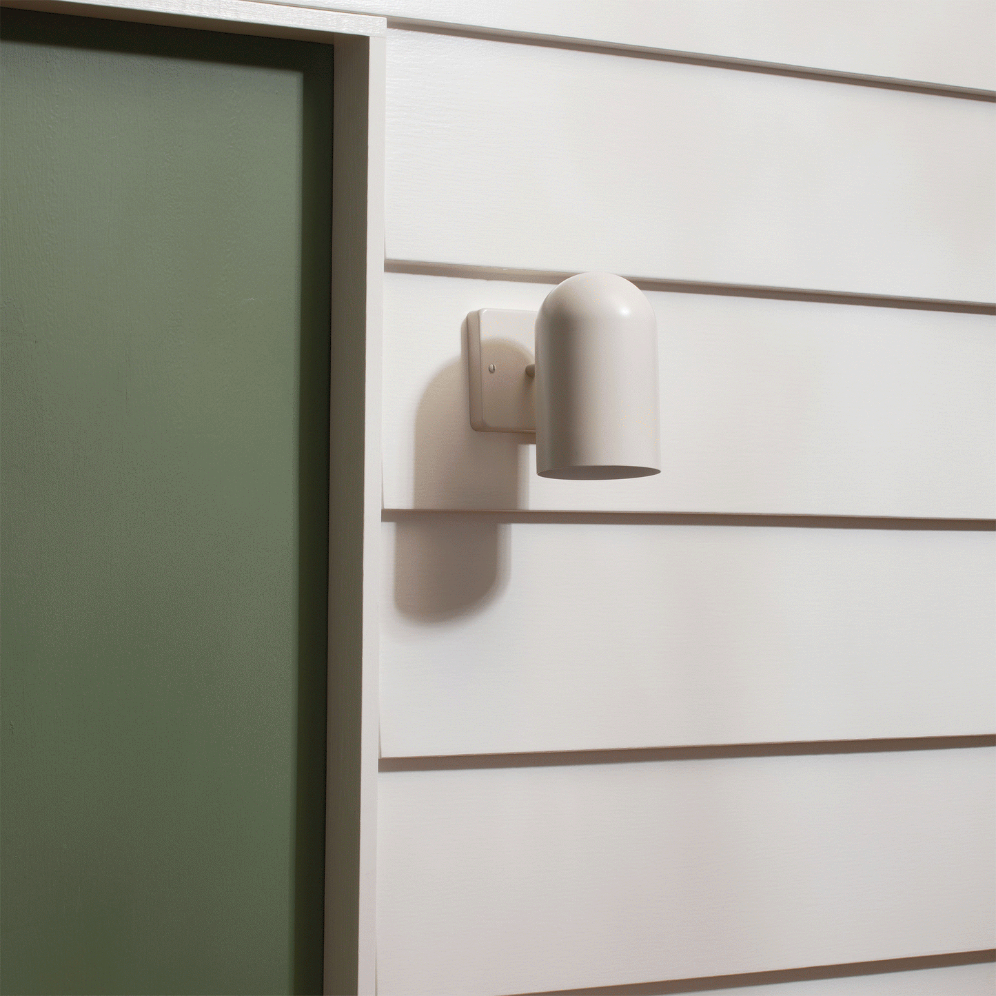 Close-up of Allegheny 4.5-inch sconce with matte white cylindrical shade and rectangular wall plate on white siding