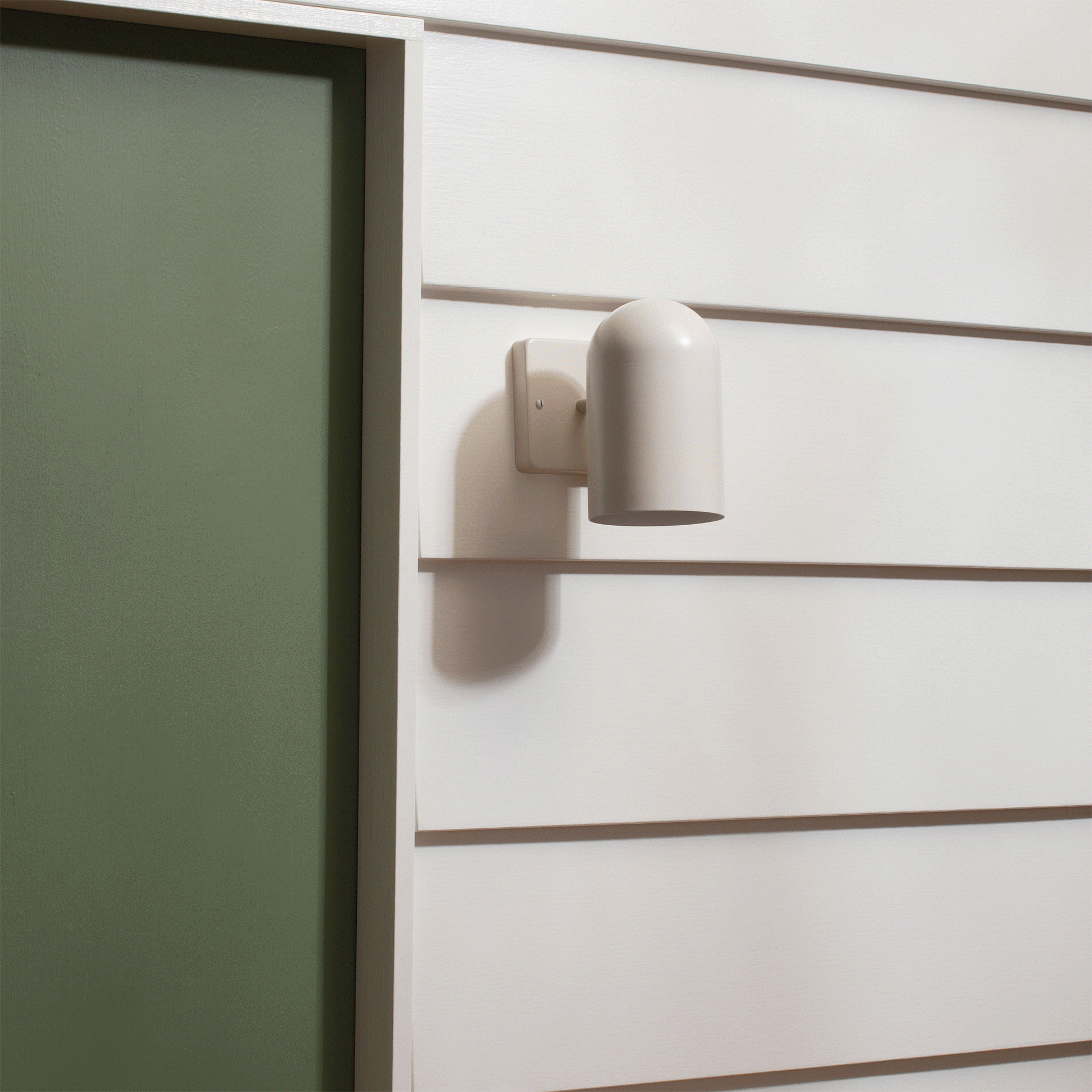 Close-up of Allegheny 4.5-inch sconce with matte white cylindrical shade and rectangular wall plate on white siding
