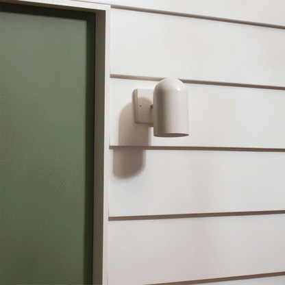 Close-up of Allegheny 4.5-inch sconce with matte white cylindrical shade and rectangular wall plate on white siding