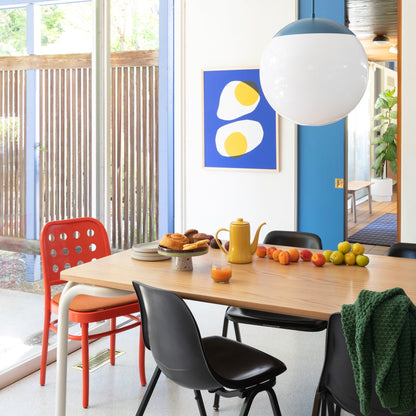 Angled view of Forma dining table showing light oak top and slim edge with mixed chairs and pendant light in dining room