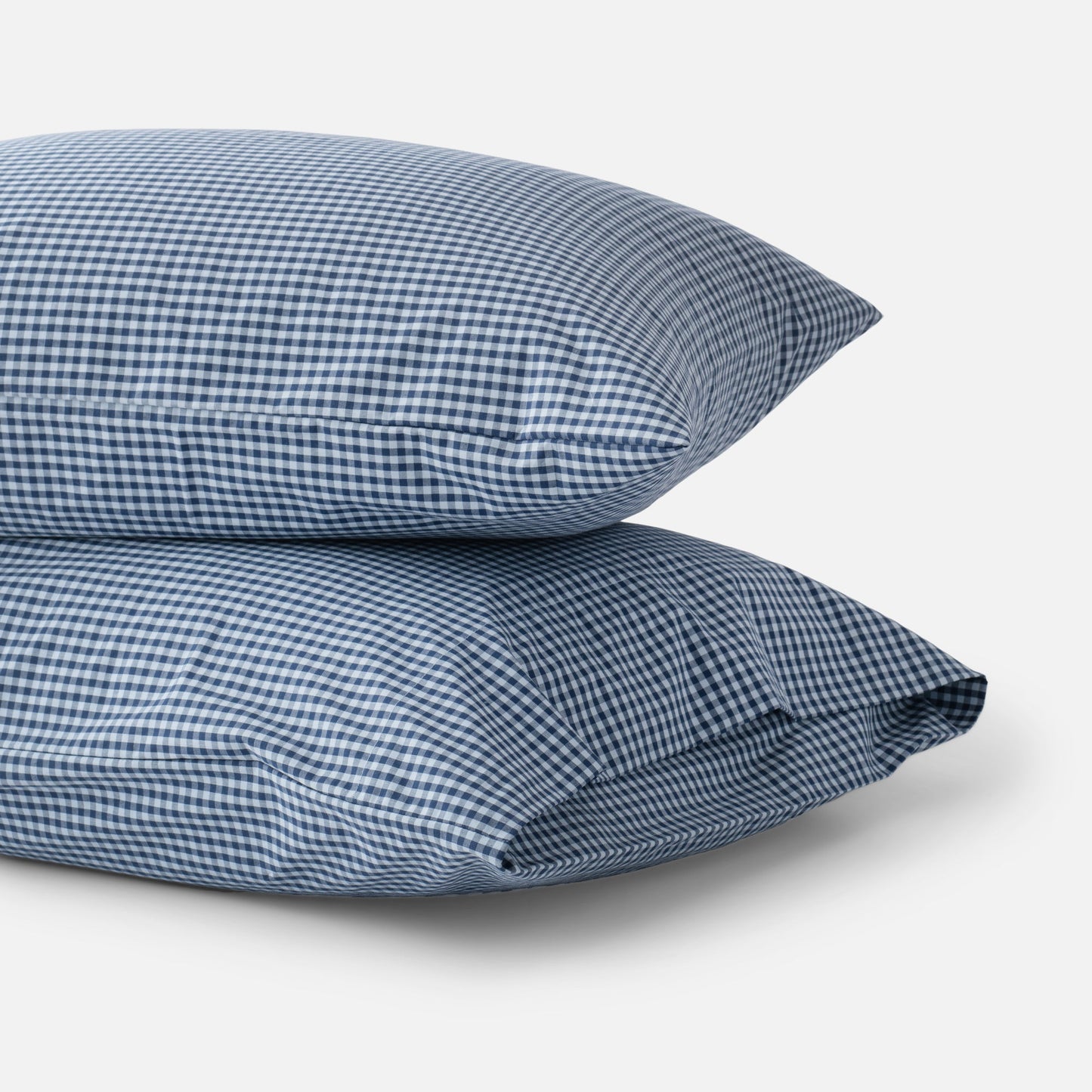Close-up of stacked Gingham Pillowcase Set (set of 2) showing navy gingham check on cotton percale against a white background