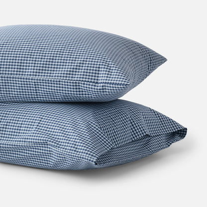Close-up of stacked Gingham Pillowcase Set (set of 2) showing navy gingham check on cotton percale against a white background