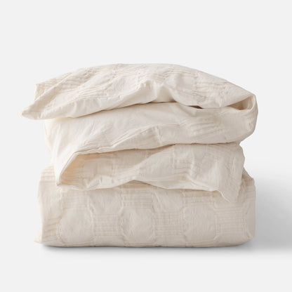 Folded stack view of Woven Tally Duvet Cover showcasing woven stitch texture in natural color on white background