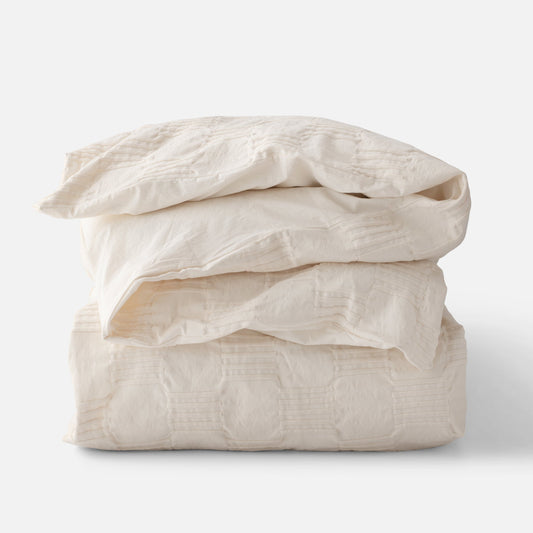 Folded stack view of Woven Tally Duvet Cover showcasing woven stitch texture in natural color on white background
