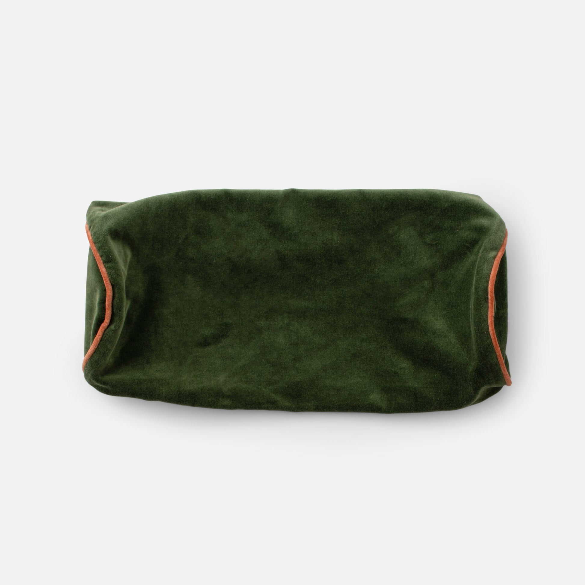 Close up top view of Velvet Piped Pillow showcasing deep green 100% cotton velvet and rust contrast piping on a light gray background