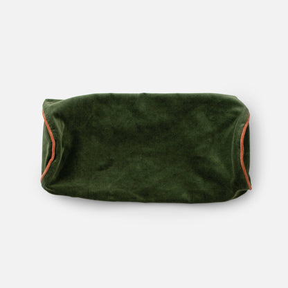Close up top view of Velvet Piped Pillow showcasing deep green 100% cotton velvet and rust contrast piping on a light gray background