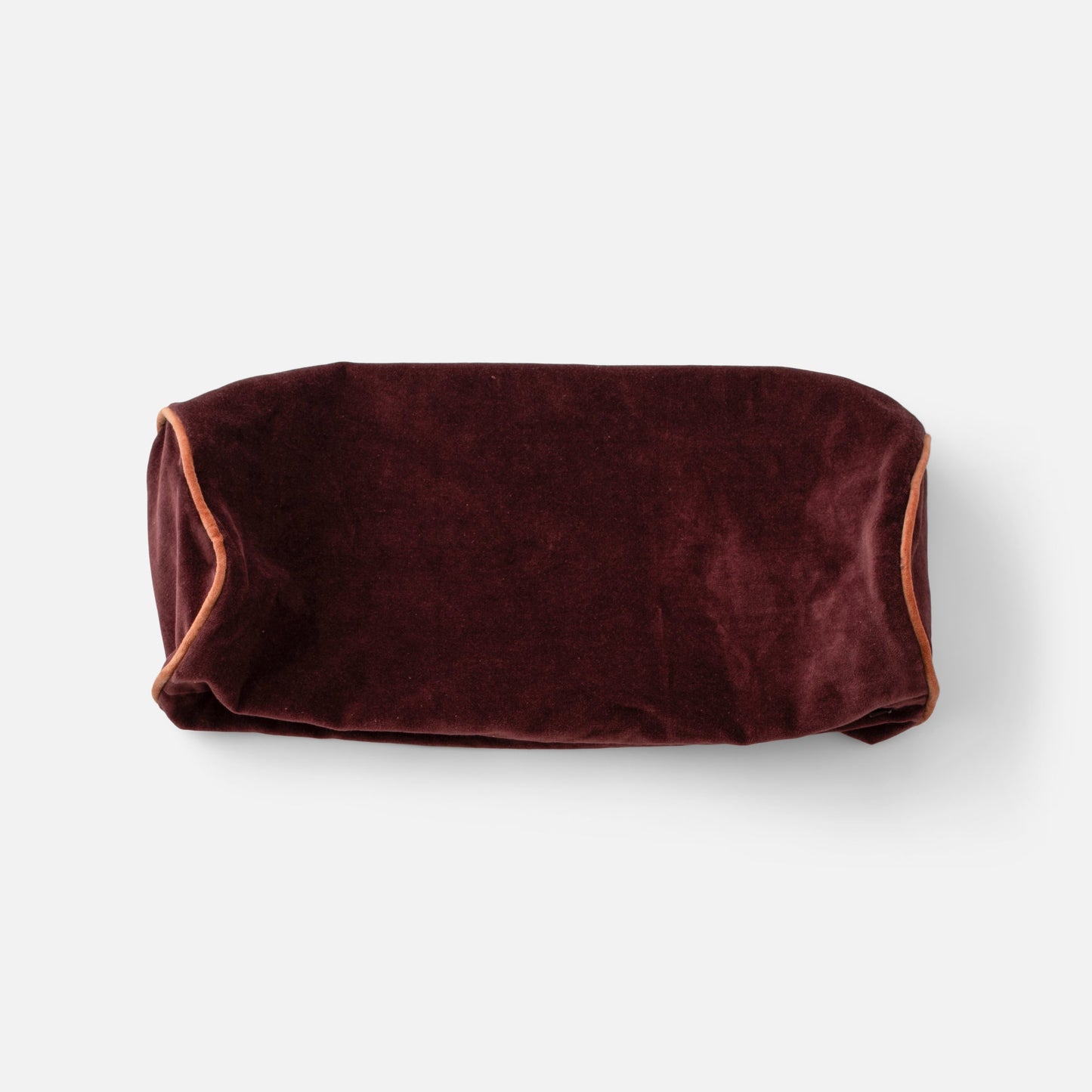 Overhead view of Velvet Piped Pillow 20 by 7 showcasing raisin velvet fabric and rust contrast piping on light gray background