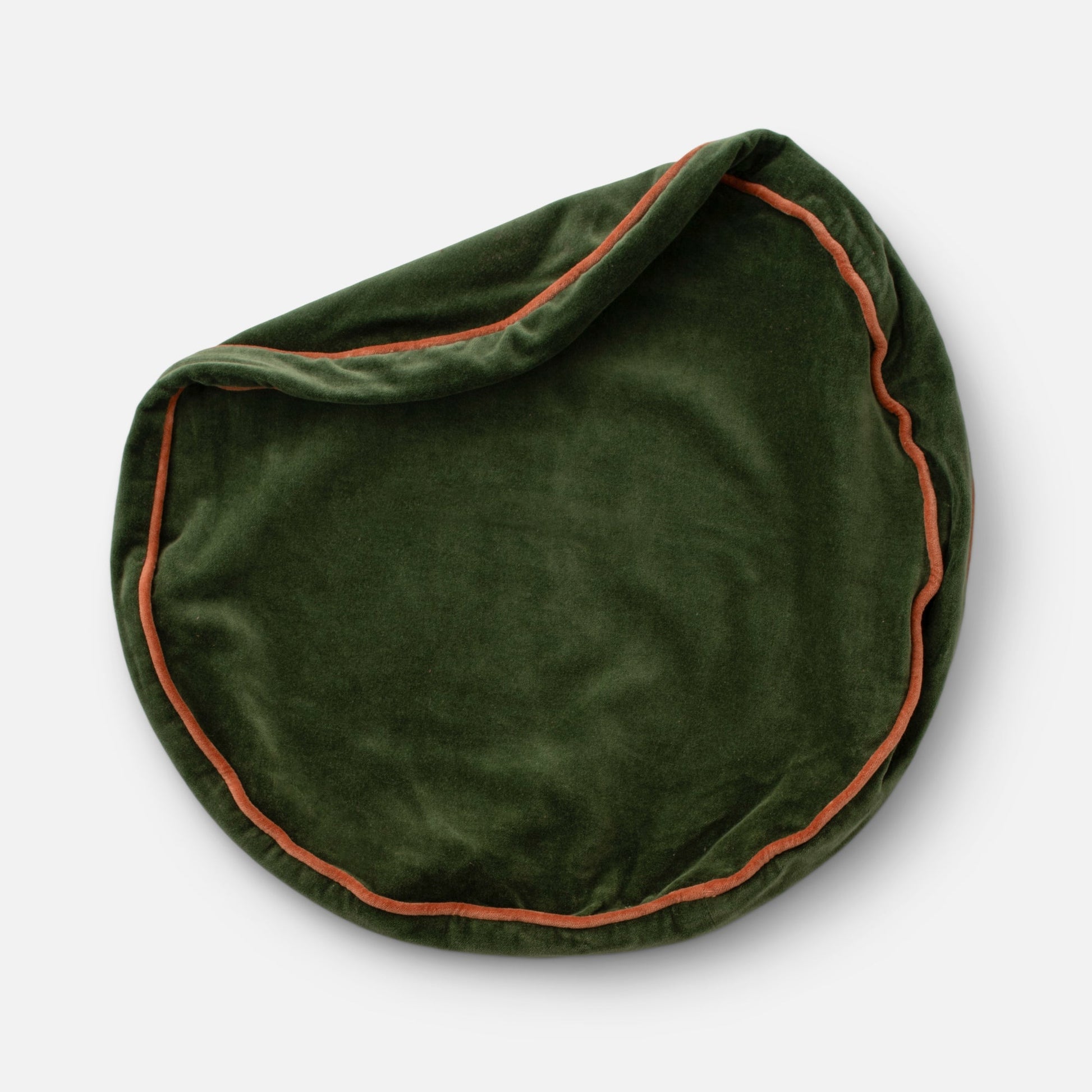 Overhead view of Velvet Piped Pillow showing round shape in dark green cotton velvet with rust contrast piping on light gray