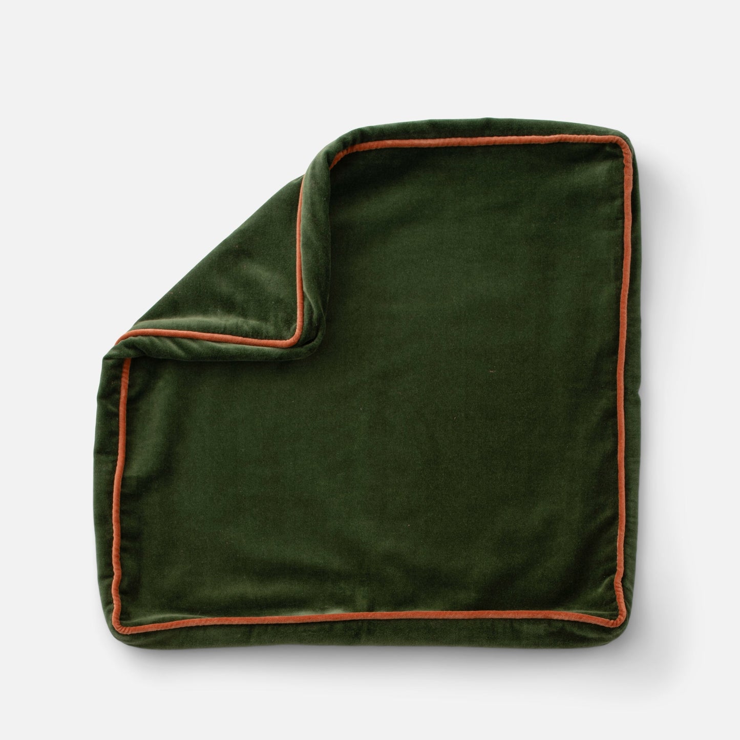 Close-up of Velvet Piped Pillow showcasing deep green cotton velvet and rust contrast piping on a light gray background