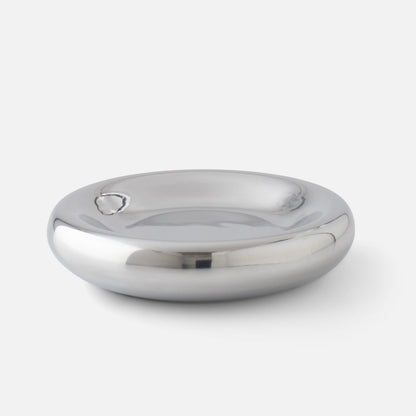 Close-up of Yves cast metal catchall showcasing polished mirrored finish and rounded shallow bowl on white background