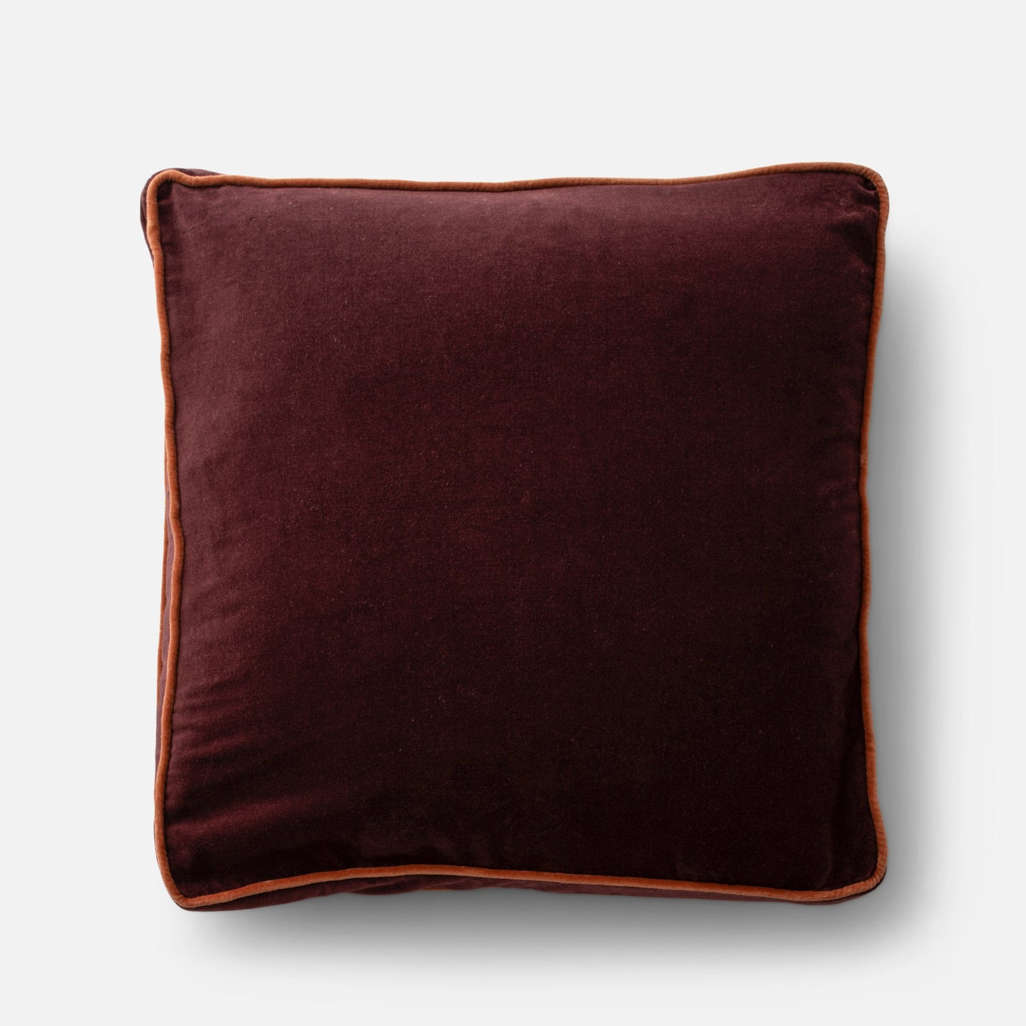 Overhead view of Velvet Piped Pillow showing raisin 100% cotton velvet and rust contrast piping on light gray background