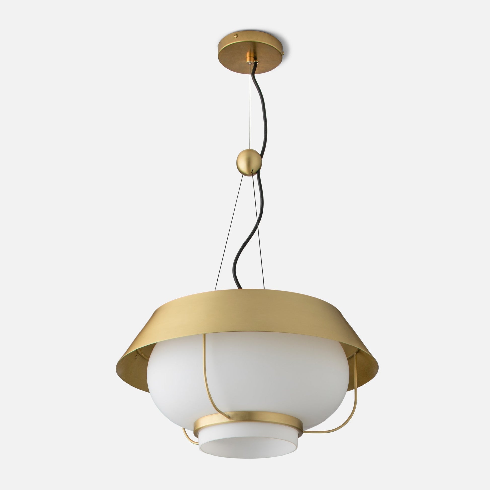 Top close-up of Alfred Pendant showcasing natural brass canopy, curved black cord, and brass counterweight against a light gray background