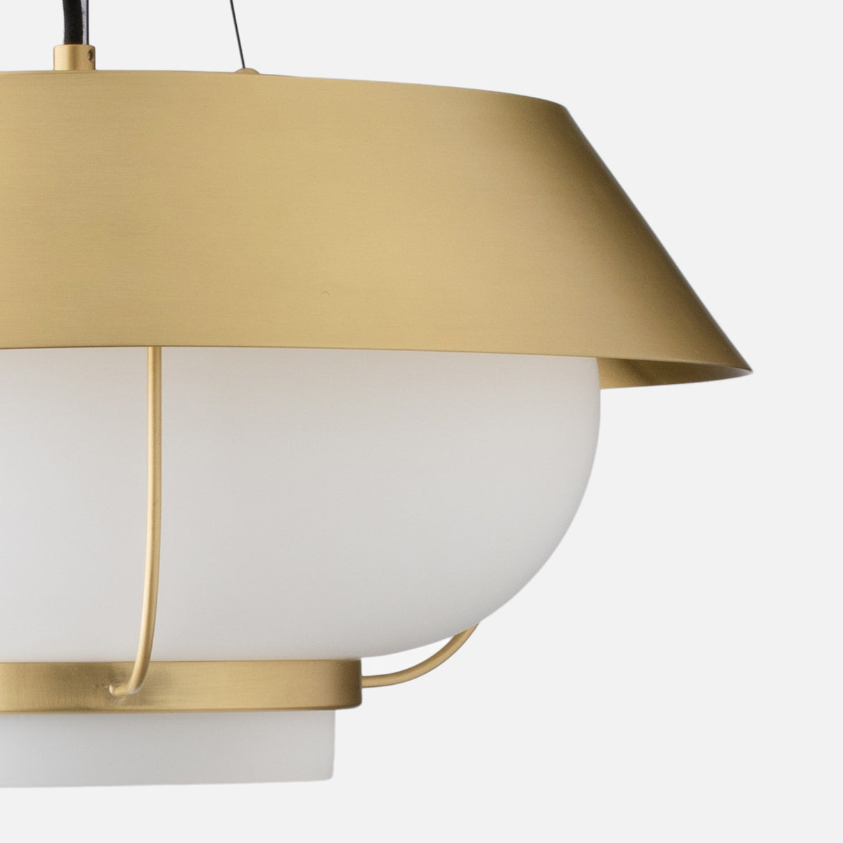 Close-up right-side view of Alfred pendant showing natural brass shade and white opal glass diffuser against light gray background