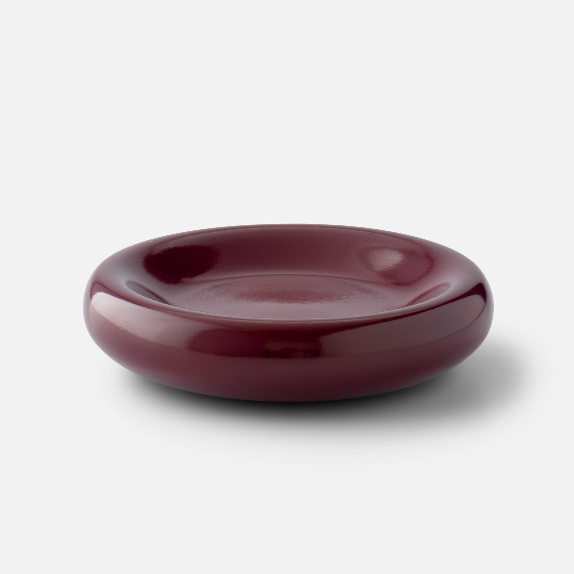 Front view of Yves cast metal catch-all showcasing glossy raisin finish and rounded low-profile shape on a white background