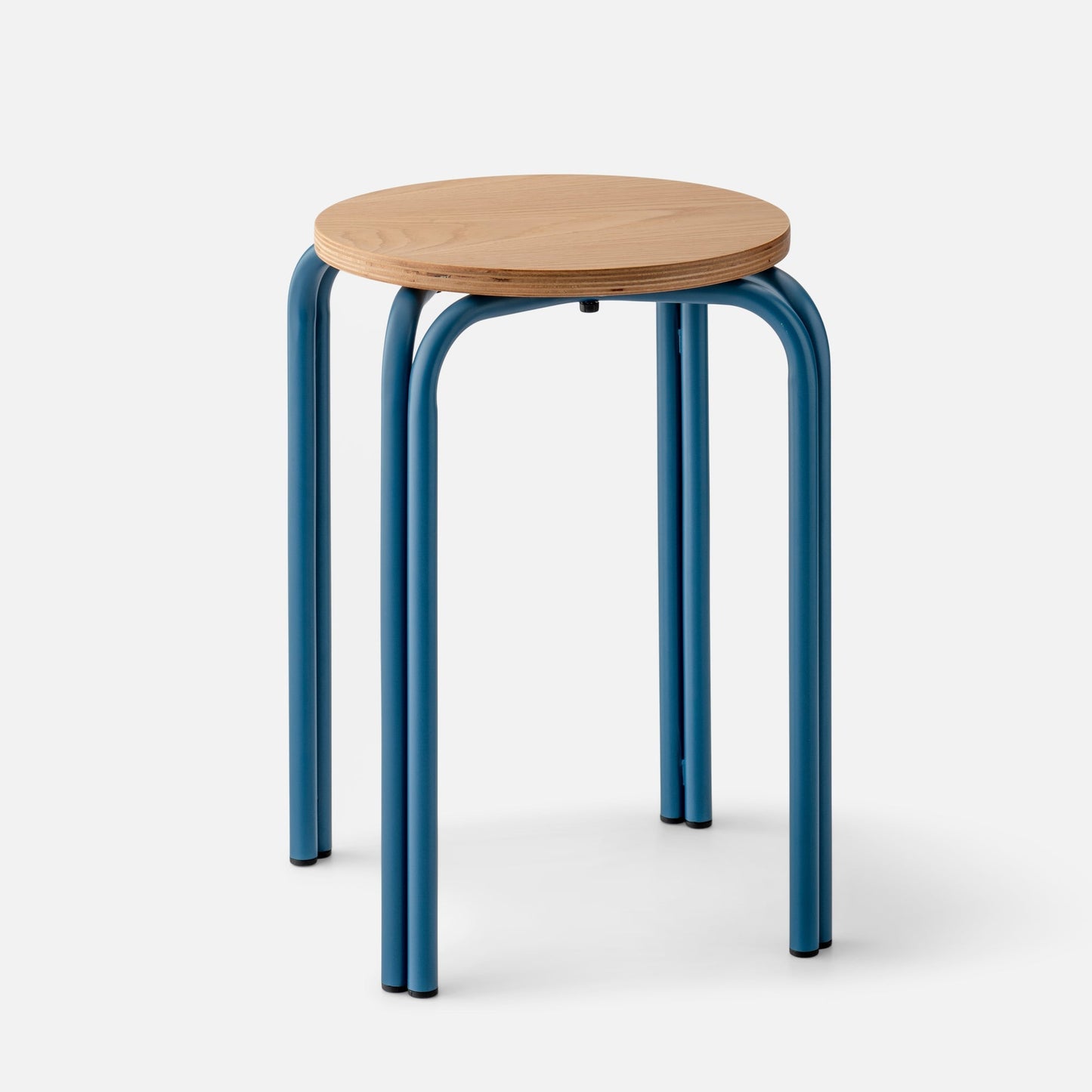 Close-up of Forma Stool showing white oak plywood top with exposed edge and indigo powder-coated steel legs on white background