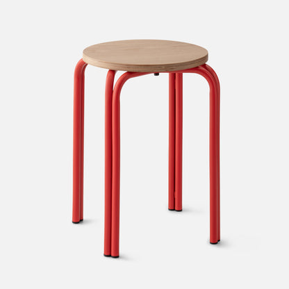 Close-up front view of Forma Stool showing a round layered plywood seat and red powder-coated tubular legs on white background