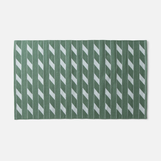 Flat-lay of Cotton Ladder flatweave rug showcasing green ladder stripe pattern and woven texture on white background