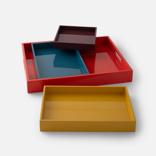 Angled top-down view of Stacking Trays, set of four, showcasing nesting design and lacquer finish in mixed muted colors on a white background
