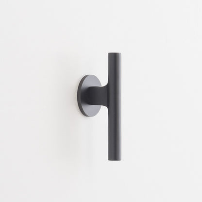 Side view of Galley Pull showing matte black cylindrical bar and round backplate on a white wall