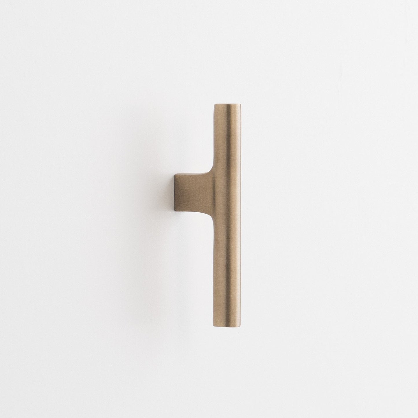 Close-up vertical view of Galley Pull showcasing its natural brass finish and asymmetrical swept curve on a white background