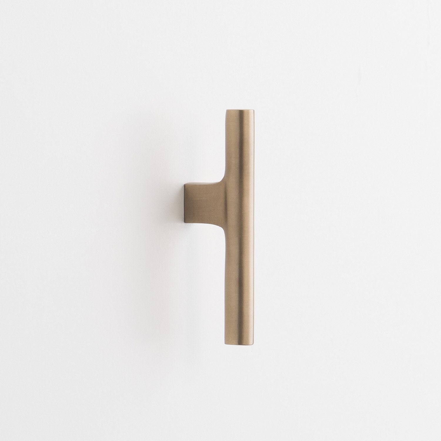 Close-up vertical view of Galley Pull showcasing its natural brass finish and asymmetrical swept curve on a white background