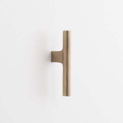 Close-up vertical view of Galley Pull showcasing its natural brass finish and asymmetrical swept curve on a white background